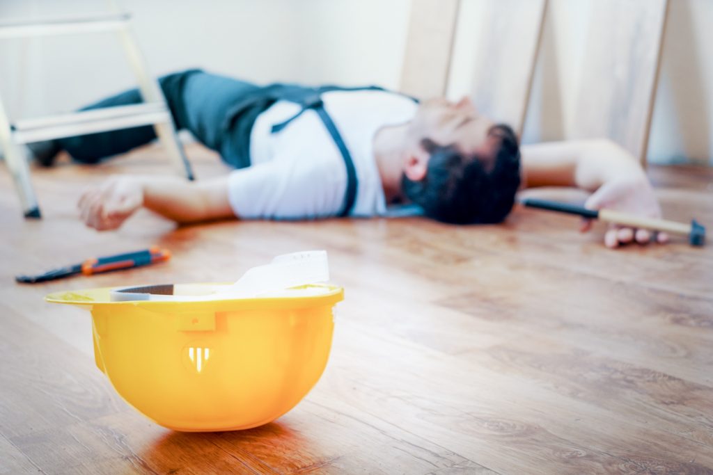 a man lying on the floor after suffering an injury in a slip, trip and fall at work