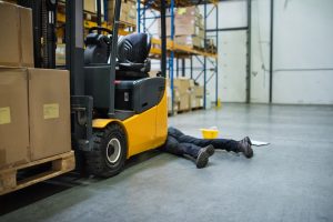 A deceased person beneath a forklift in a warehouse. 