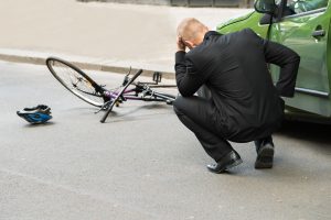 An uninsured and upset driver looks at a bike on the road. 