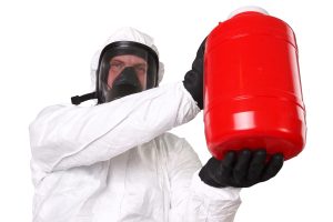 A worker in a protective suit holding a red container.