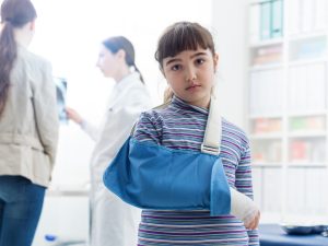 A young girl with her arm in a cast standing in a doctor's office.