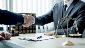 A No Win No Fee solicitor agrees to represent a case that includes a claim for loss of earnings by shaking hands over a desk. 