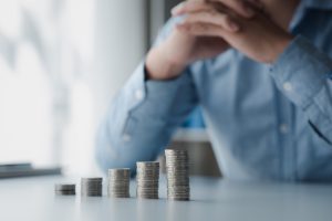 A man looks at the stacks of coins he has left after suffering ongoing loss. 