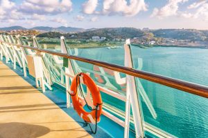 The railing of a cruise ship with a life bouy on the side, docking for a shore excursion