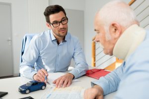 A LAWYER EXPLAINING INTERIM PAYMENTS FROM THEIR FINAL COMPENSATION SETTLEMENT TO A CLIENT IN A NECK BRACE.